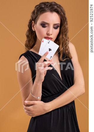 Beautiful brown-haired woman holding two aces as a sign for poker game, gambling and casino Beautiful brown-haired woman holding two aces as a sign for poker game, gambling and casino 92521974