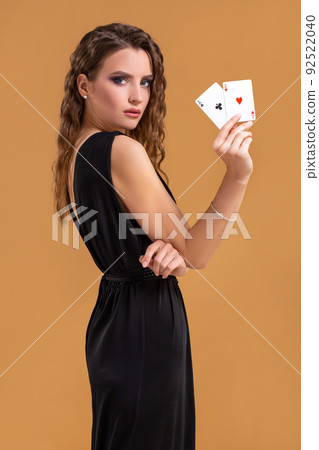 Beautiful brown-haired woman holding two aces as a sign for poker game, gambling and casino Beautiful brown-haired woman holding two aces as a sign for poker game, gambling and casino 92522040