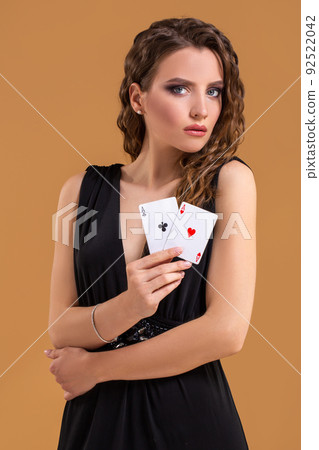 Beautiful brown-haired woman holding two aces as a sign for poker game, gambling and casino Beautiful brown-haired woman holding two aces as a sign for poker game, gambling and casino 92522042