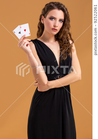 Beautiful brown-haired woman holding two aces as a sign for poker game, gambling and casino Beautiful brown-haired woman holding two aces as a sign for poker game, gambling and casino 92522061