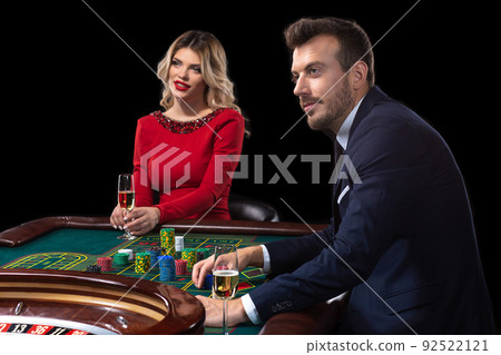 A beautiful young woman and a man are sitting at a roulette table. Casino. 92522121