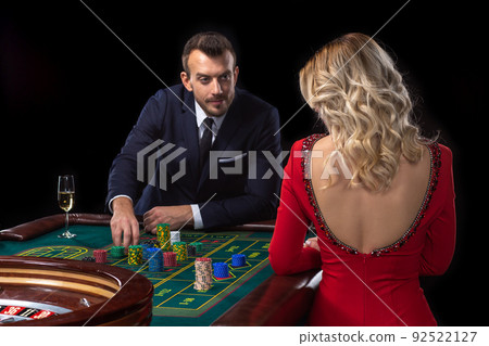A beautiful young woman and a man are sitting at a roulette table. Casino. 92522127