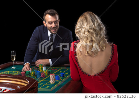 A beautiful young woman and a man are sitting at a roulette table. Casino. A beautiful young woman and a man are sitting at a roulette table. Casino. 92522136