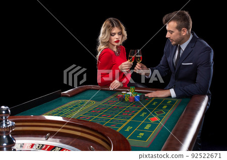 Beautiful and well dressed couple playing roulette in the casino Beautiful and well dressed couple playing roulette in the casino 92522671