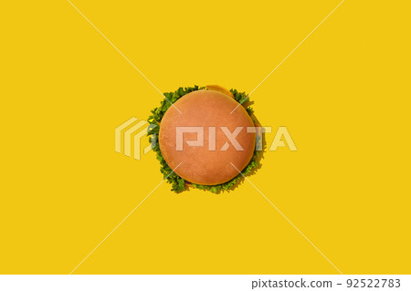 Tasty fresh unhealthy hamburger with ketchup and vegetables on yellow vibrant bright background. Top View with Copy Space. Tasty fresh unhealthy hamburger with ketchup and vegetables on yellow vibrant bright background. Top View with Copy Space. 92522783