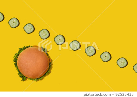 Tasty fresh unhealthy hamburger with ketchup and vegetables on yellow vibrant bright background. Top View with Copy Space. Tasty fresh unhealthy hamburger with ketchup and vegetables on yellow vibrant bright background. Top View with Copy Space. 92523433
