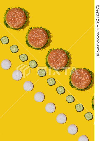 Many tasty fresh unhealthy hamburgers with ketchup and vegetables on yellow vibrant bright background. Top View with Copy Space. Many tasty fresh unhealthy hamburgers with ketchup and vegetables on yellow vibrant bright background. Top View with Copy Space. 92523475
