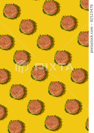 Many tasty fresh unhealthy hamburgers with ketchup and vegetables on yellow vibrant bright background. Top View with Copy Space. Many tasty fresh unhealthy hamburgers with ketchup and vegetables on yellow vibrant bright background. Top View with Copy Space. 92523476