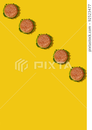Many tasty fresh unhealthy hamburgers with ketchup and vegetables on yellow vibrant bright background. Top View with Copy Space. Many tasty fresh unhealthy hamburgers with ketchup and vegetables on yellow vibrant bright background. Top View with Copy Space. 92523477