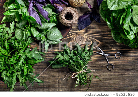 Variety of fresh organic herbs on wooden background. Freshly harvested herbs including basil, arugula. Top view. Copy space. Variety of fresh organic herbs on wooden background. Freshly harvested herbs including basil, arugula. Top view. Copy space. 92523656