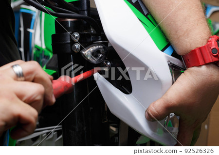 Installing the front lamp with a plastic lining on the motorcycle. 92526326