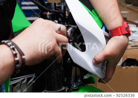 Installing the front lamp with a plastic lining on the motorcycle. 92526336