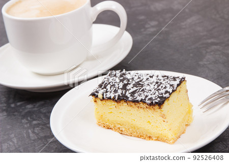 Cup of white coffee and fresh baked cheesecake. Delicious dessert Cup of white coffee and fresh baked cheesecake. Delicious dessert 92526408