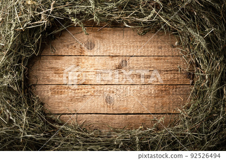 Frame from dry straw hay on vintage wooden board 92526494