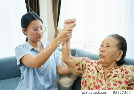 Asian elder woman doing a physical therapy exercise with her granddaughter, wellness - wellbeing and health care in elder people in aging society concept. Asian elder woman doing a physical therapy exercise with her granddaughter, wellness - wellbeing and health care in elder people in aging society concept. 92527263