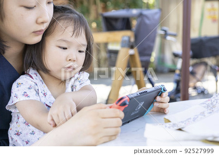 一個蹣跚學步的孩子在玩遊戲,一個姐姐在看它 一個蹣跚學步的孩子在玩遊戲,一個姐姐在看它 92527999