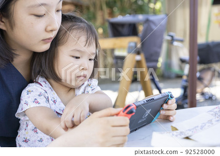 一個蹣跚學步的孩子在玩遊戲,一個姐姐在看它 一個蹣跚學步的孩子在玩遊戲,一個姐姐在看它 92528000