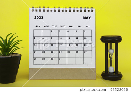 May 2023 desk calendar with table plant and minutes glass on yellow background. May 2023 desk calendar with table plant and minutes glass on yellow background. 92528036