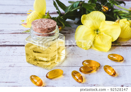 Evening primrose oil in bottle, softgels and flowers on wooden table Evening primrose oil in bottle, softgels and flowers on wooden table 92528147