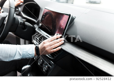Woman twists the controls on the car radio. Listening to the radio in the car. Woman twists the controls on the car radio. Listening to the radio in the car. 92528412