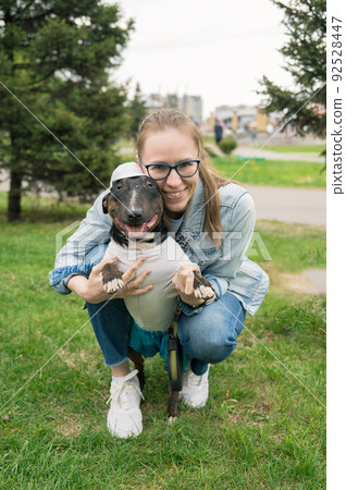 Woman walking with bull terrier outdoors Woman walking with bull terrier outdoors 92528447