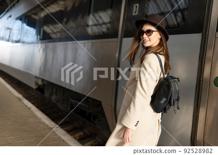Beautiful traveler with backpack on the platform of the railway station. Young woman near train.. 92528982
