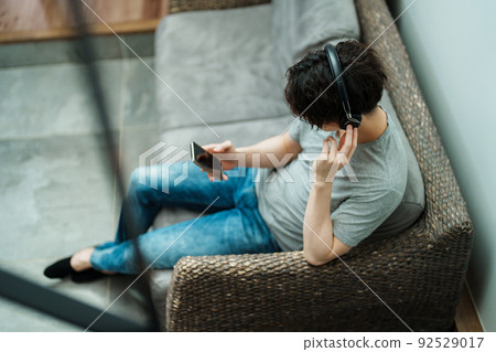 A young man listening to music on a smartphone A young man listening to music on a smartphone 92529017