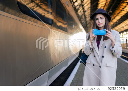Female tourist at the railway station wearing on mask before entering of the train car. Pandemic concept 92529059