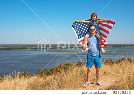 Happy family father and child with usa flag enjoying nature. Free lifestyle 92529230