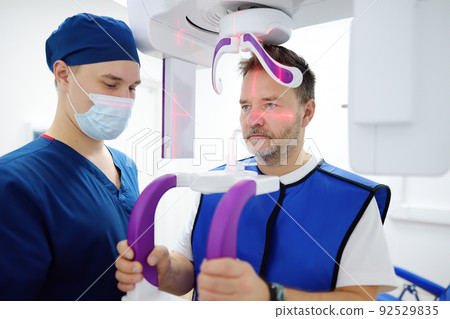Doctor dentist are going to do a digital x-ray with man patient in dentistry clinic. Panoramic radiography. Modern professional dental equipment Doctor dentist are going to do a digital x-ray with man patient in dentistry clinic. Panoramic radiography. Modern professional dental equipment 92529835