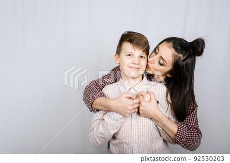 Parenting teen boys, Raising a teen. Studio portrait of Happy Teen boy hugging his mom 92530203