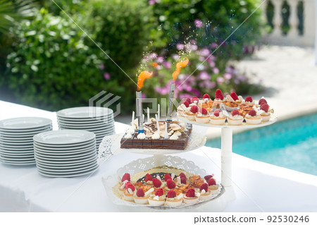 Dessert buffet, small chocolate and strawberry cakes, birthday candles by the pool. Dessert buffet, small chocolate and strawberry cakes, birthday candles by the pool. 92530246