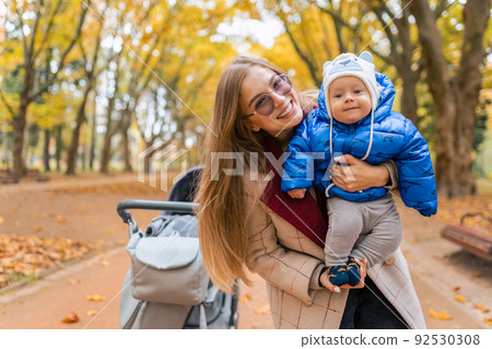 Cheerful mom with baby in hands in the park Cheerful mom with baby in hands in the park 92530308