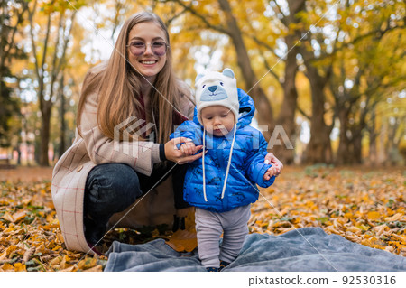 Mom teaches the kid to walk. .Young mother walks in the park with baby Mom teaches the kid to walk. .Young mother walks in the park with baby 92530316