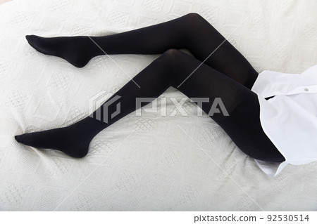 Beautiful long female legs in stockings. Girl putting on stockings at home in a white room. Black tights. Varicose veins prevention. Woman body in underwear. Beautiful long female legs in stockings. Girl putting on stockings at home in a white room. Black tights. Varicose veins prevention. Woman body in underwear. 92530514