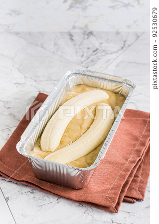 Raw dough for banana bread in a baking dish on the table. Social media trendy. Vertical view Raw dough for banana bread in a baking dish on the table. Social media trendy. Vertical view 92530679