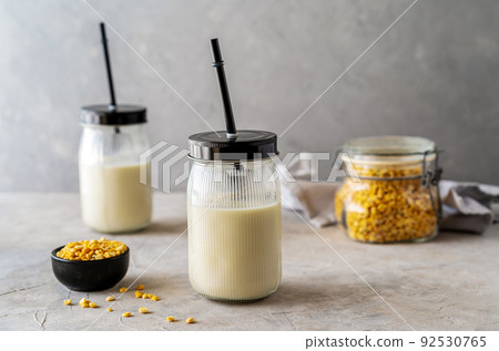 Vegan healthy pea milk in glass jars with drinking straws, concrete background, pea grains and mockup place Vegan healthy pea milk in glass jars with drinking straws, concrete background, pea grains and mockup place 92530765