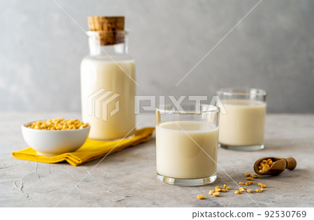 Vegan healthy pea milk in glass bottle and two glasses, concrete background, pea grains, yellow napkin. Copy space Vegan healthy pea milk in glass bottle and two glasses, concrete background, pea grains, yellow napkin. Copy space 92530769