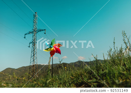 Concept of transition to alternative generation of green energy, pinwheel and power line on a natural background Concept of transition to alternative generation of green energy, pinwheel and power line on a natural background 92531149