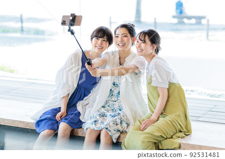 Three women taking pictures while enjoying a footbath on a girls' trip 92531481