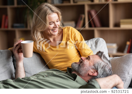 Cheerful Middle Aged Couple Resting Together At Home, Drinking Coffee And Chatting 92531721