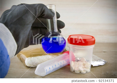 the laboratory assistant of the customs laboratory shows a flask with a positive test result for opiate content in samples, a short focus, vignetting 92534371