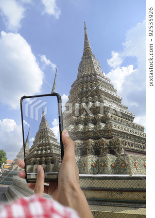 Someone hand taking picture at beautiful chedi with smartphone. 92535926