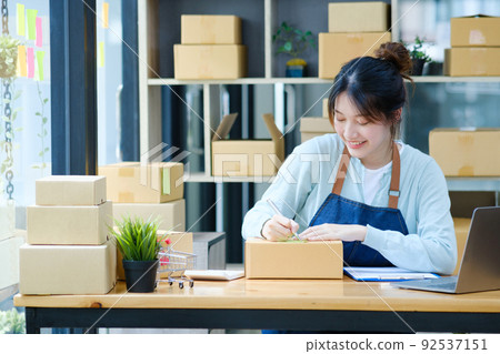 Online small business owner writing address on parcel box. 92537151