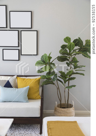 Simple, industrial interior design of living room with table standing in front of a gray sofa with yellow and blue cushions and a green plant Scandinavian interior. Simple, industrial interior design of living room with table standing in front of a gray sofa with yellow and blue cushions and a green plant Scandinavian interior. 92538155