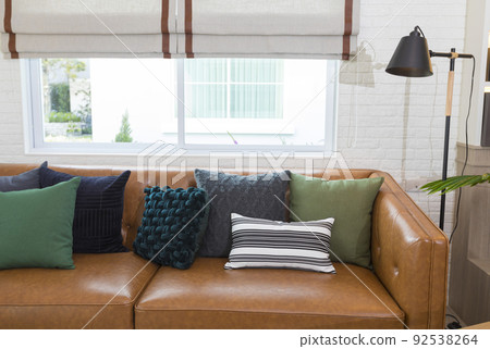 Light modern living room with brown leather couch and white, grey and green pillow on it. Light modern living room with brown leather couch and white, grey and green pillow on it. 92538264