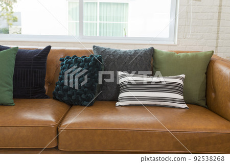 Light modern living room with brown leather couch and white, grey and green pillow on it. Light modern living room with brown leather couch and white, grey and green pillow on it. 92538268