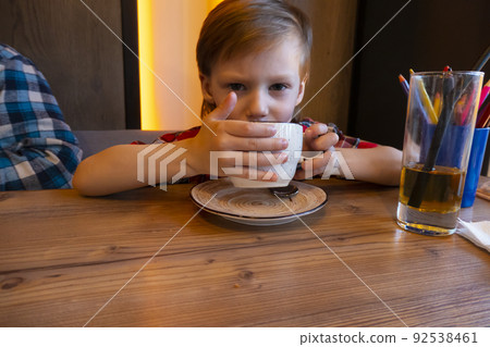 Portrait of child drinking tea in cafe Portrait of child drinking tea in cafe 92538461