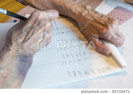 the hand of an elderly woman with bruises write the score in a card game 92538472