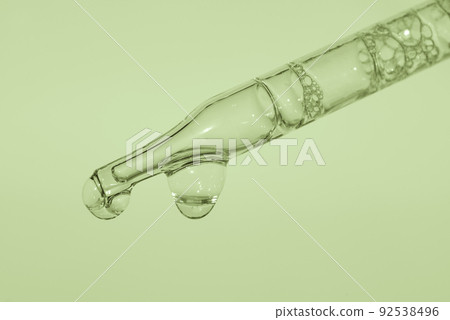 Pipette with liquid essence on a light green background With air inside. This is the consistency of micellar water. The concept of an extract for cosmetic purposes. High quality photo 92538496